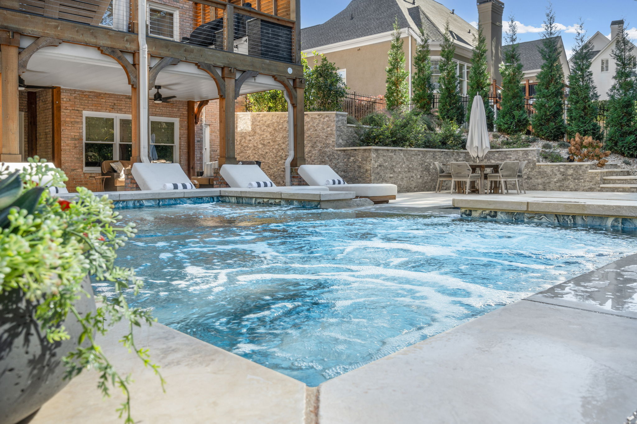 Elegant modern swimming pool with raised spa, clean architectural lines, and beautifully designed landscape.