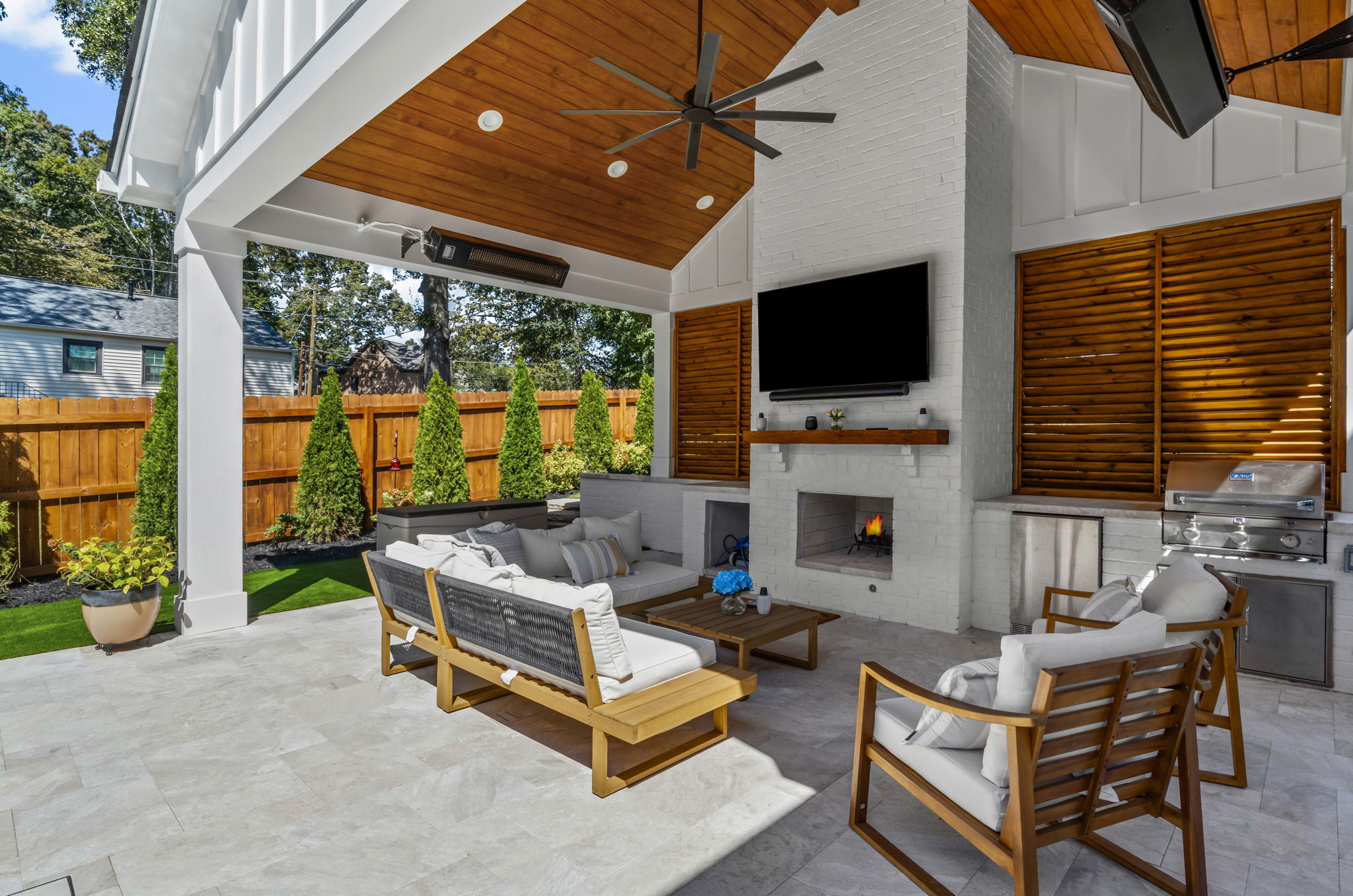 Outdoor living space with custom cabana, stone fireplace, professional landscape design, and integrated hardscape seating.